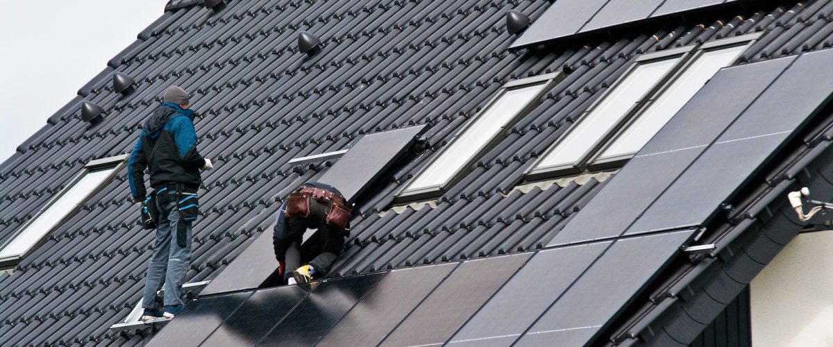 Men installing new solar panels on the roof of a private house. Green renewable energy concept.